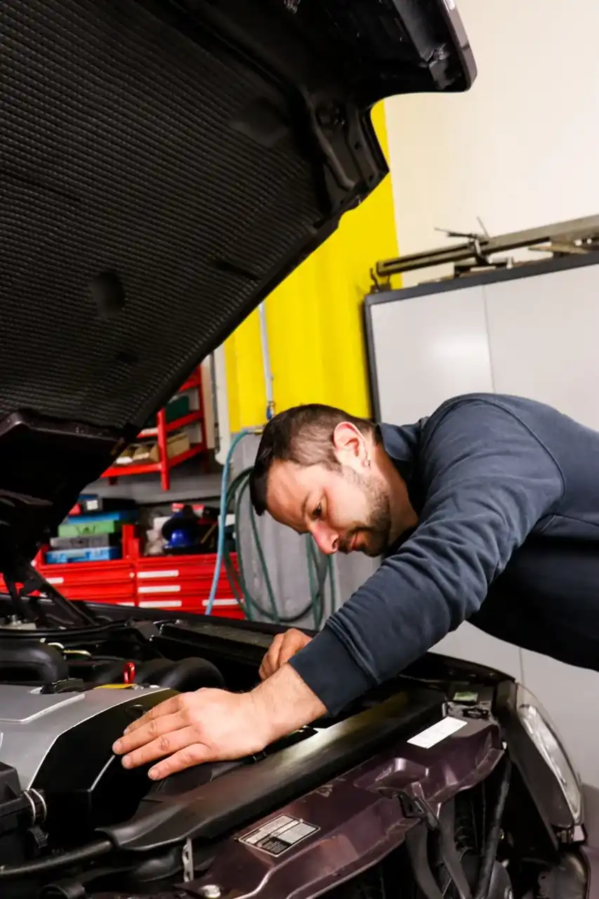 Mechaniker beugt sich über den geöffneten Motorraum