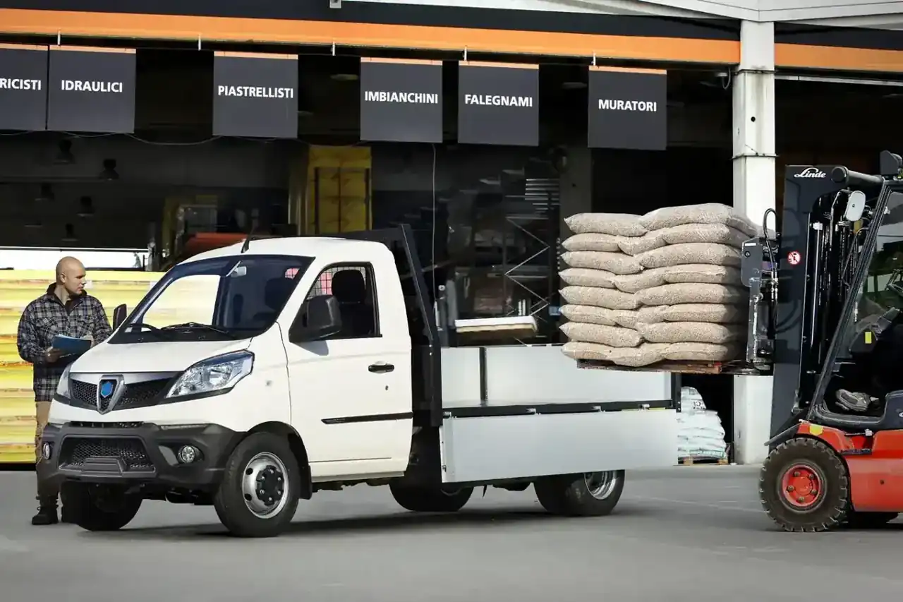 Weißer Piaggio Porter mit Pritsche wird mit dem Stapler beladen