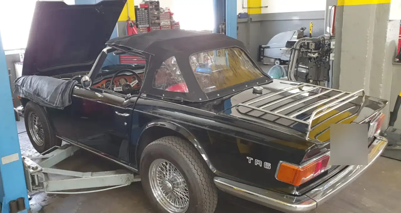 Triumph TR6 in Schwarz mit Gepäckträger in der Werkstatt