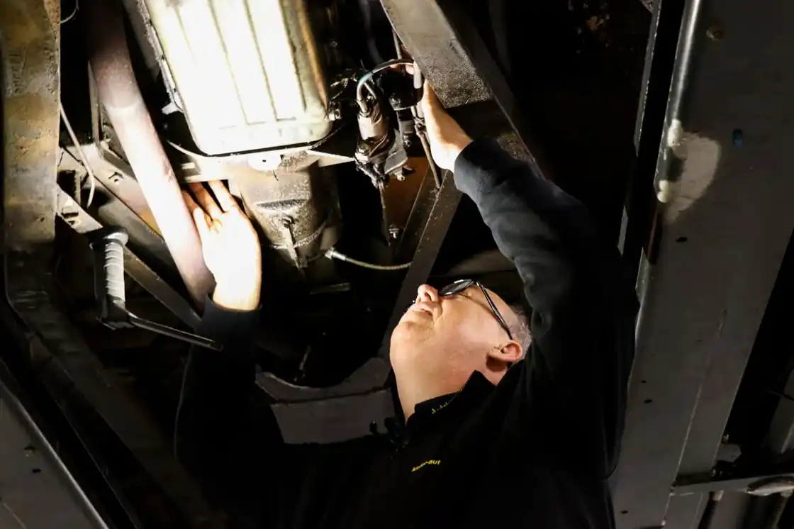 Mechaniker arbeitet unter einem Fahrzeug auf der Hebebühne